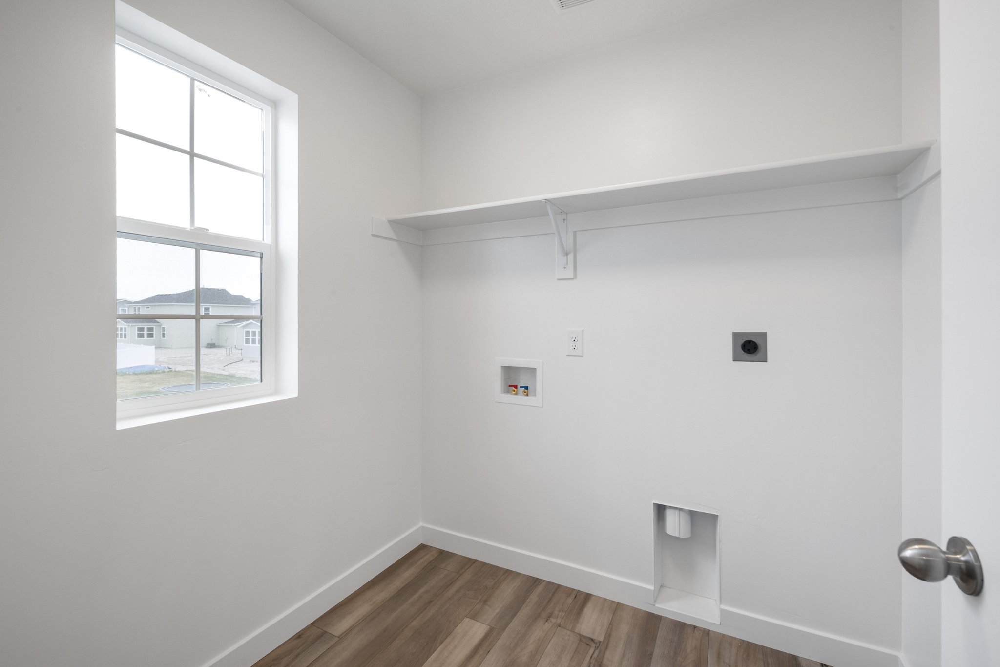 A room with a window and a wood floor.