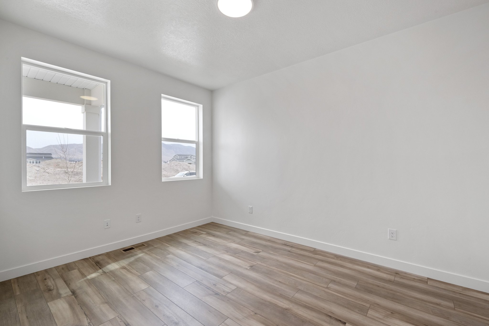 A room with a wood floor and a window with a painting on the wall.