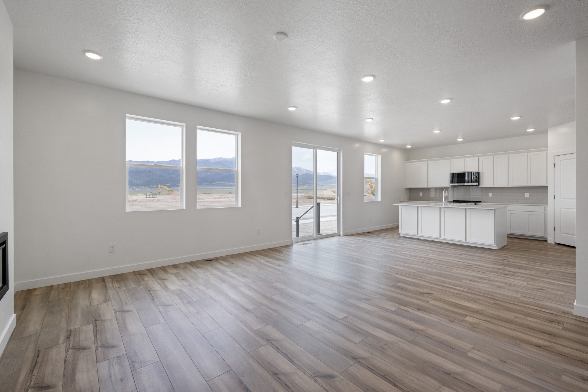 A large empty room with a wood floor and white cabinets.