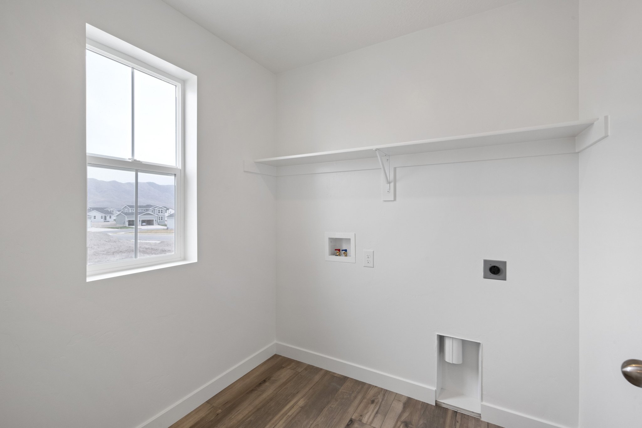 A room with a window and a wood floor.