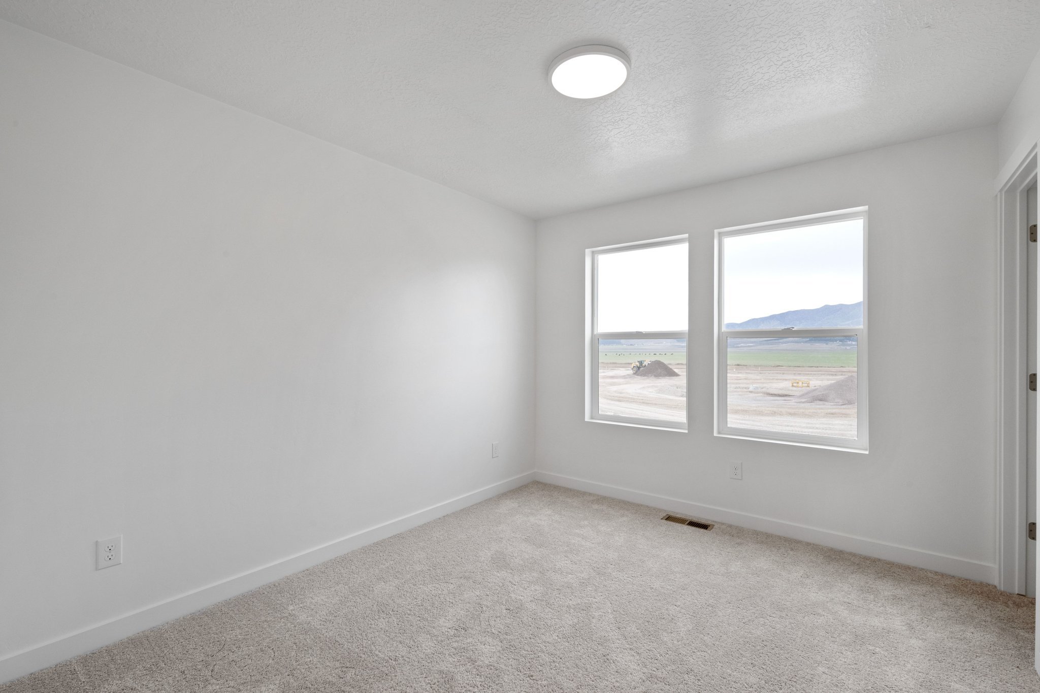 A room with a window and a light on the wall.