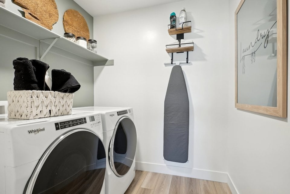 A white laundry room with a shelf and a basket with clothes on it.