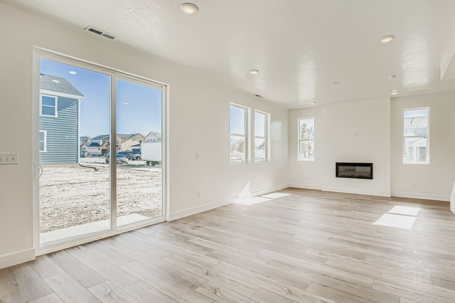 A room with a wood floor and a glass door with a view of the city.