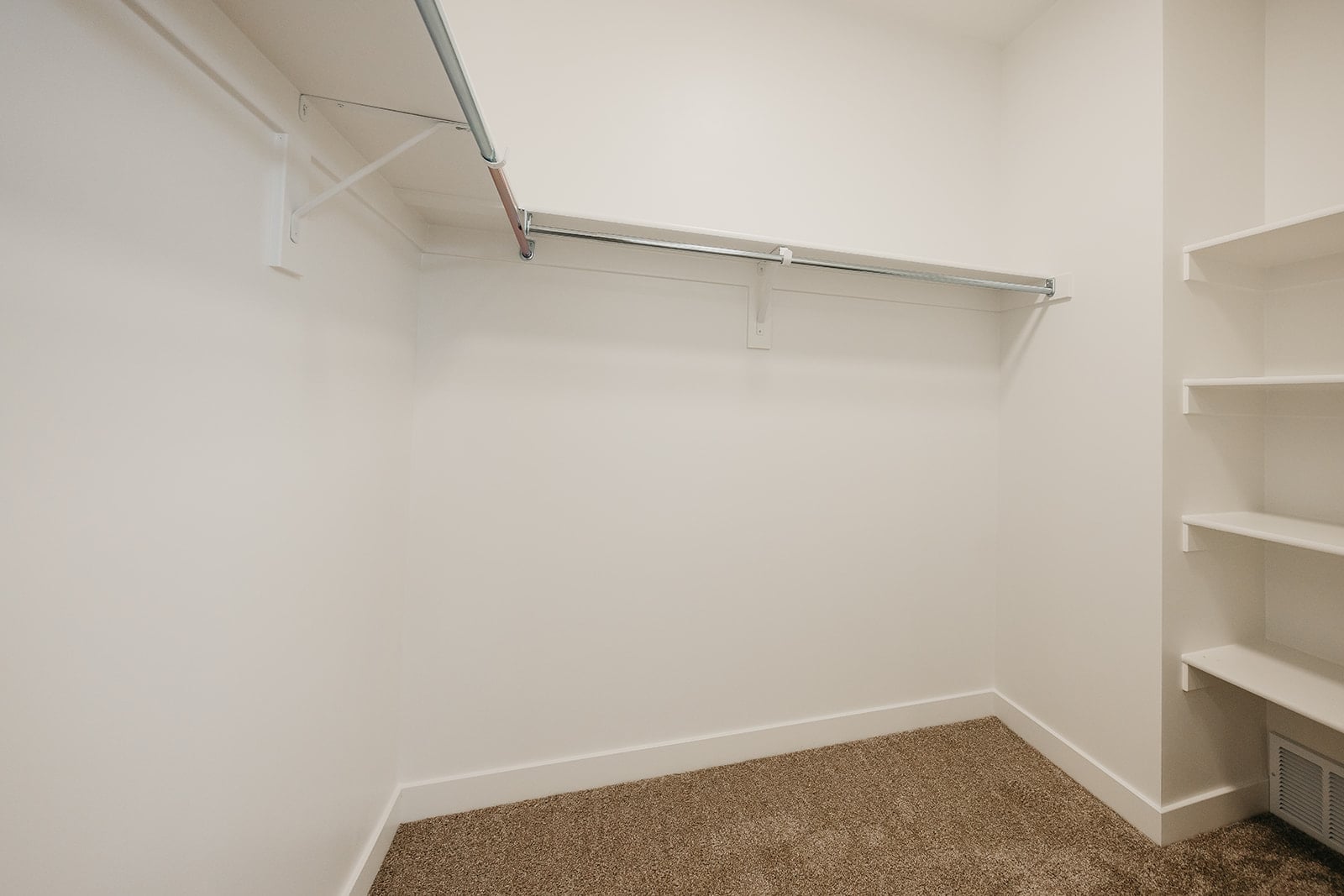 A white room with a carpet and shelves.