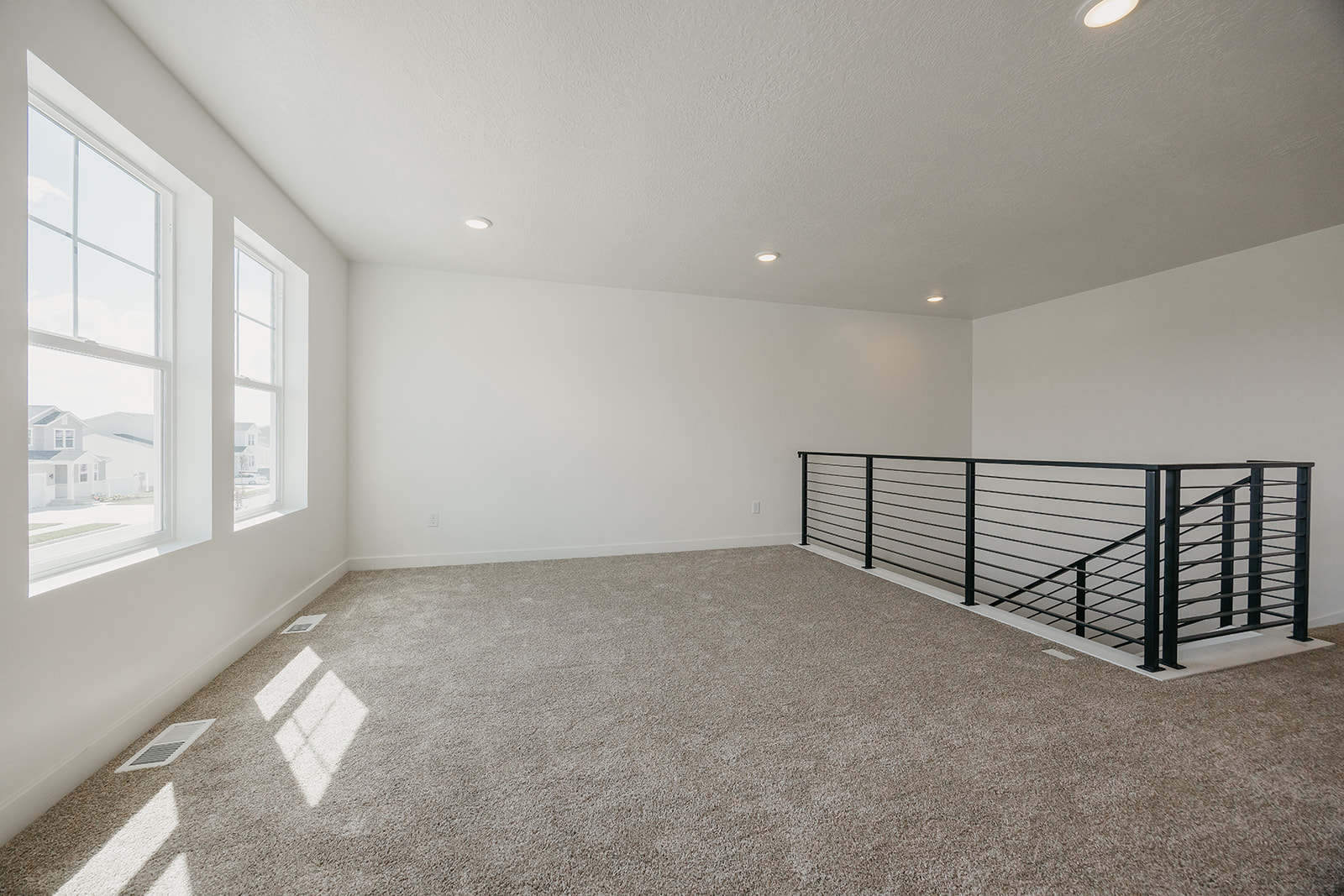 A room with a black railing and a window with a railing.