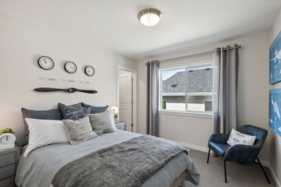 A bedroom with a bed and a chair.
