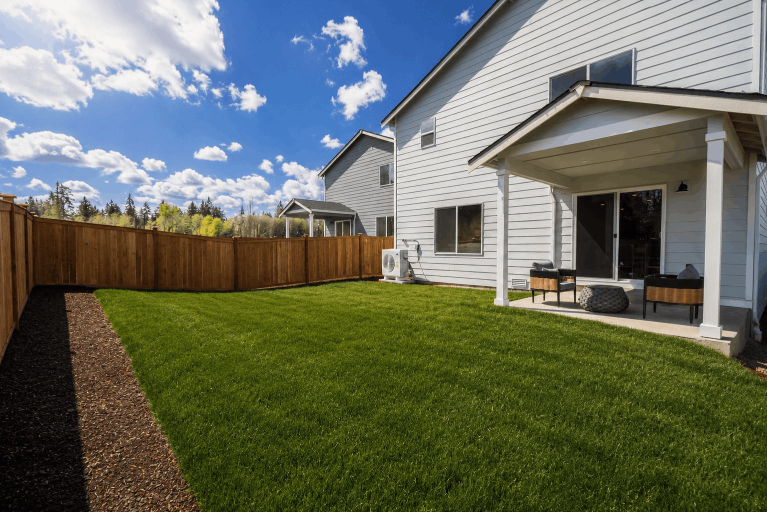A backyard with a fence and a house.