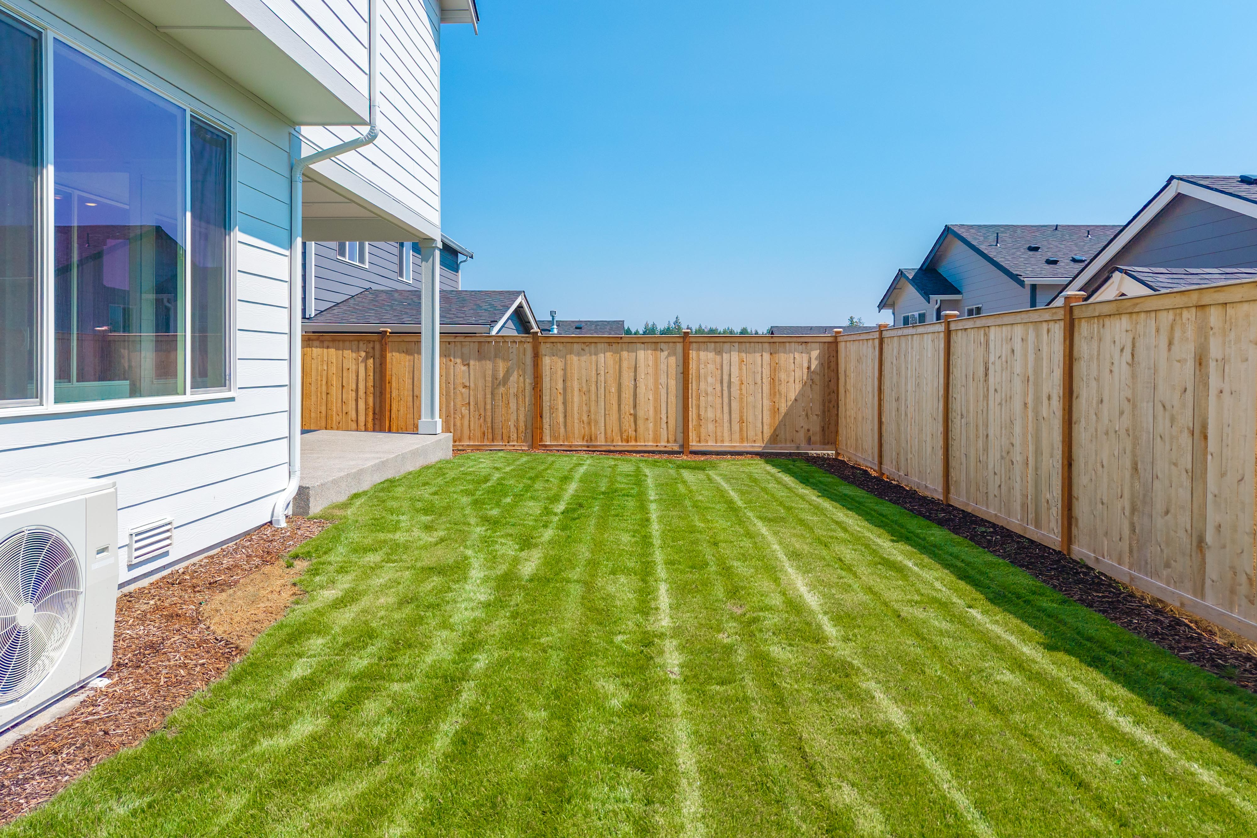 A backyard with a fence and a green lawn.