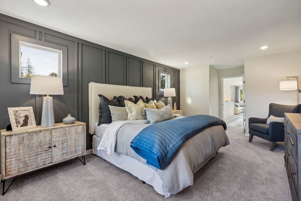 A bedroom with a bed and a chair.