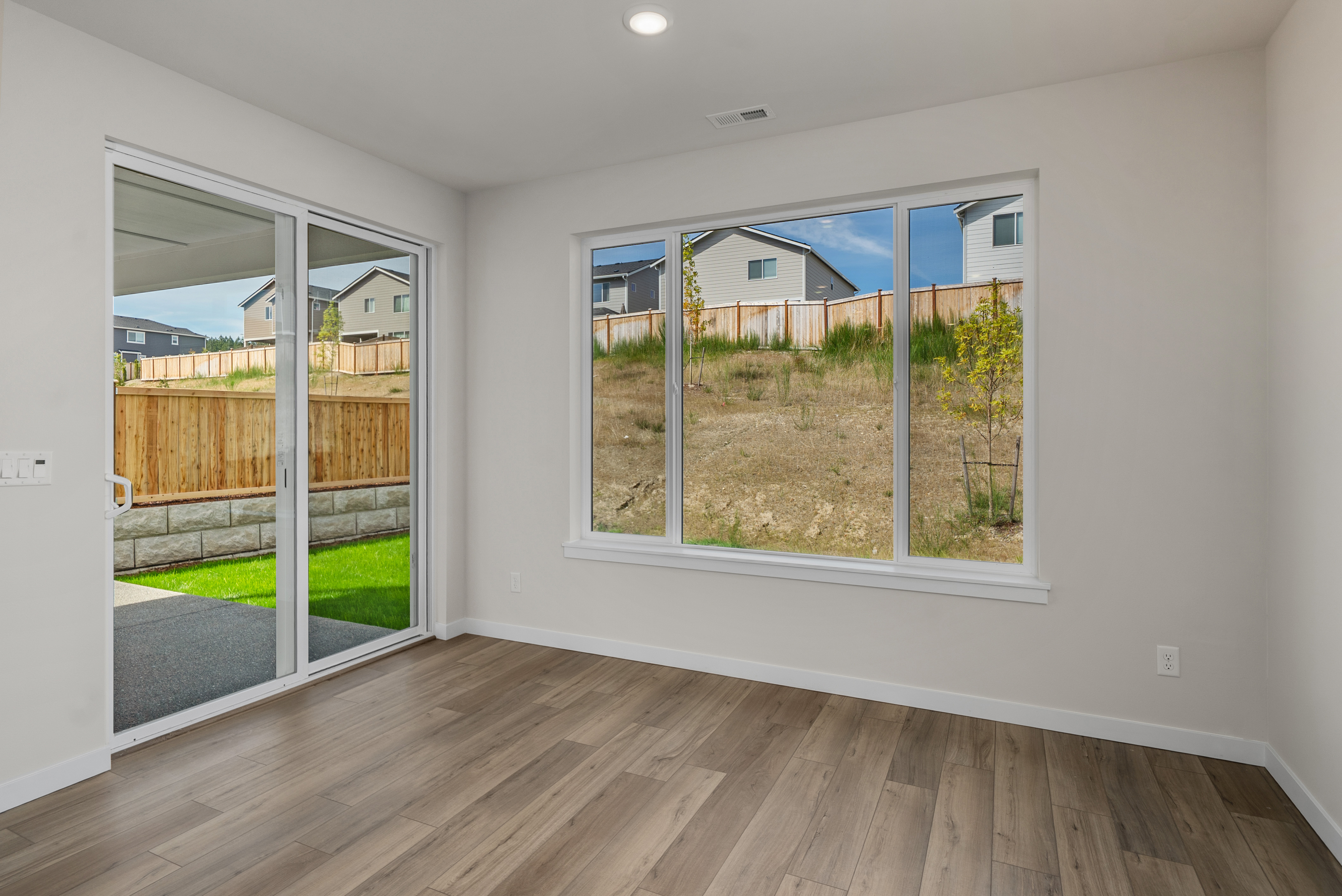 A room with a wood floor and a large window with a view of the water.