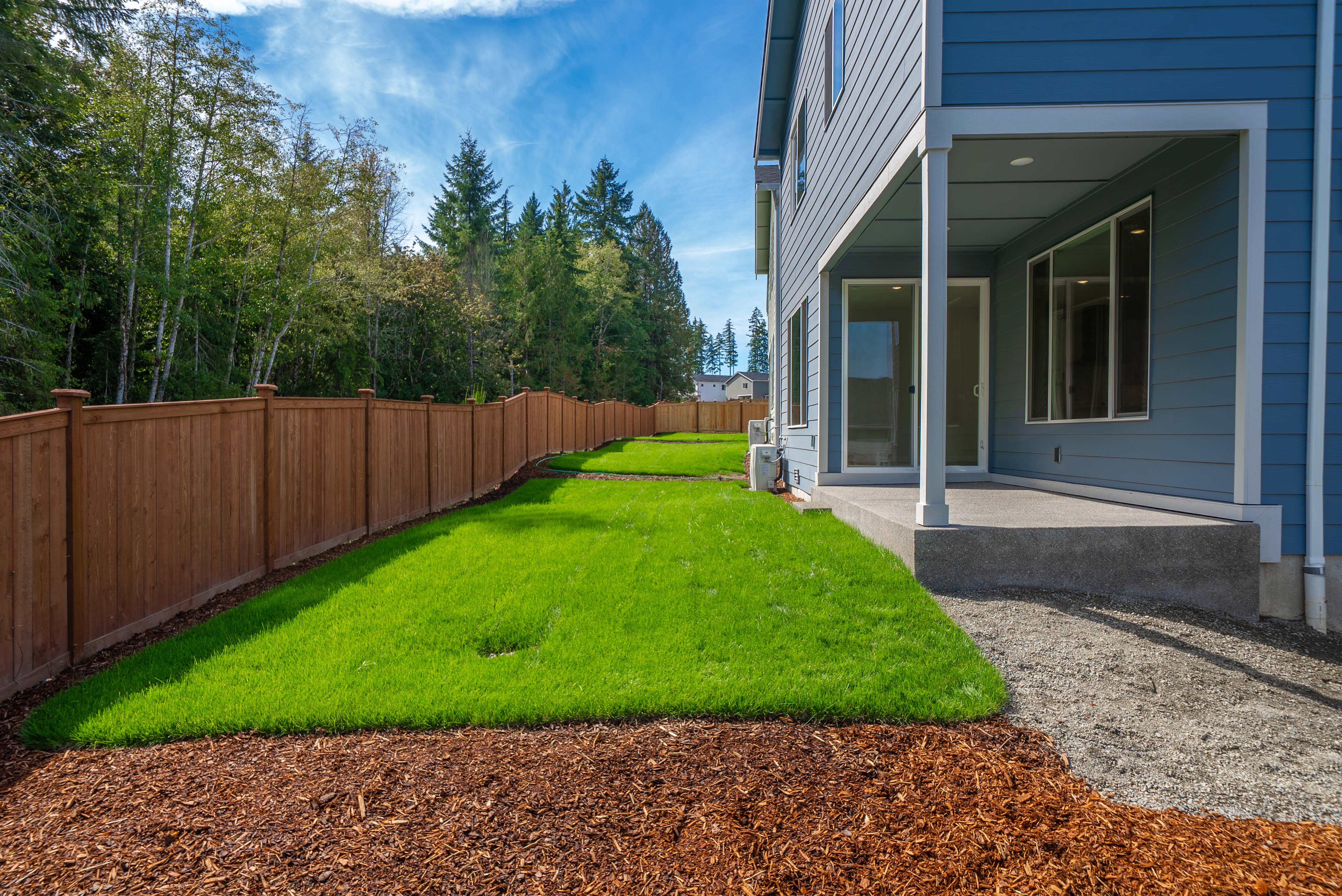 A house with a fence and a yard with trees in the background.