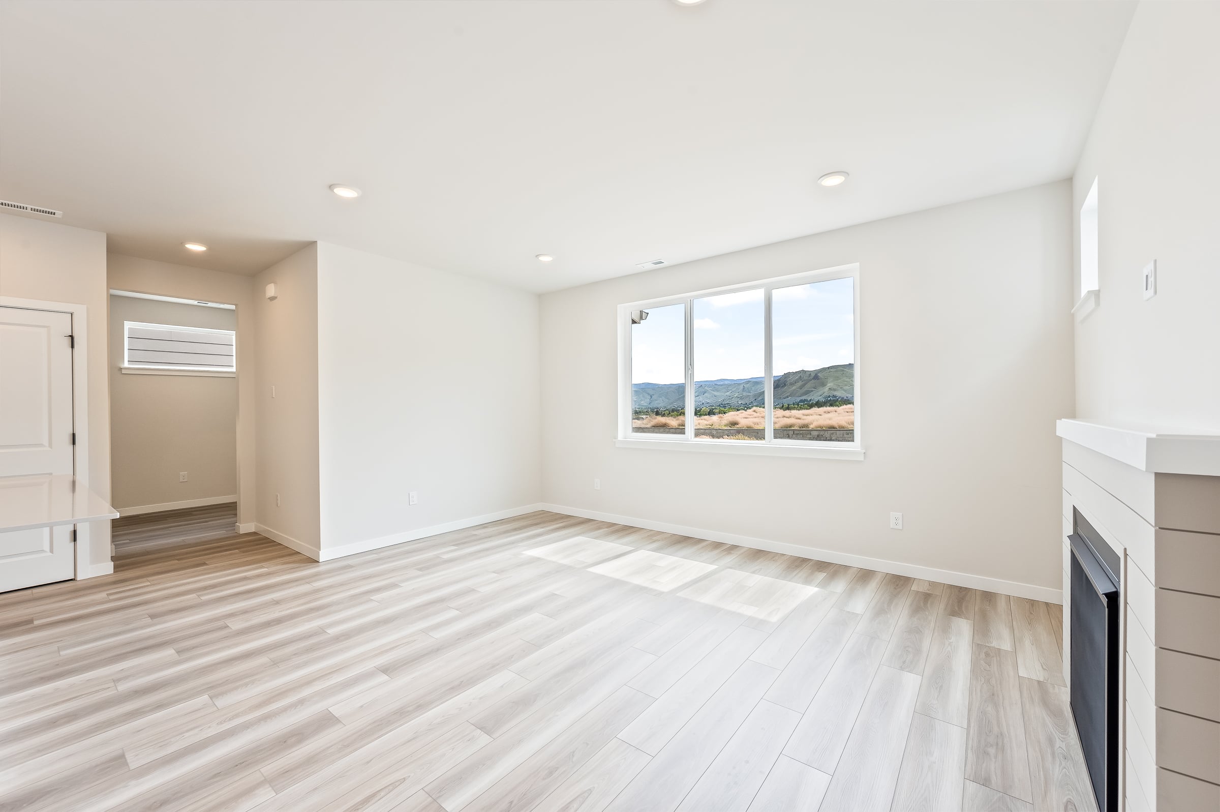 A large empty room with a wood floor and a window.