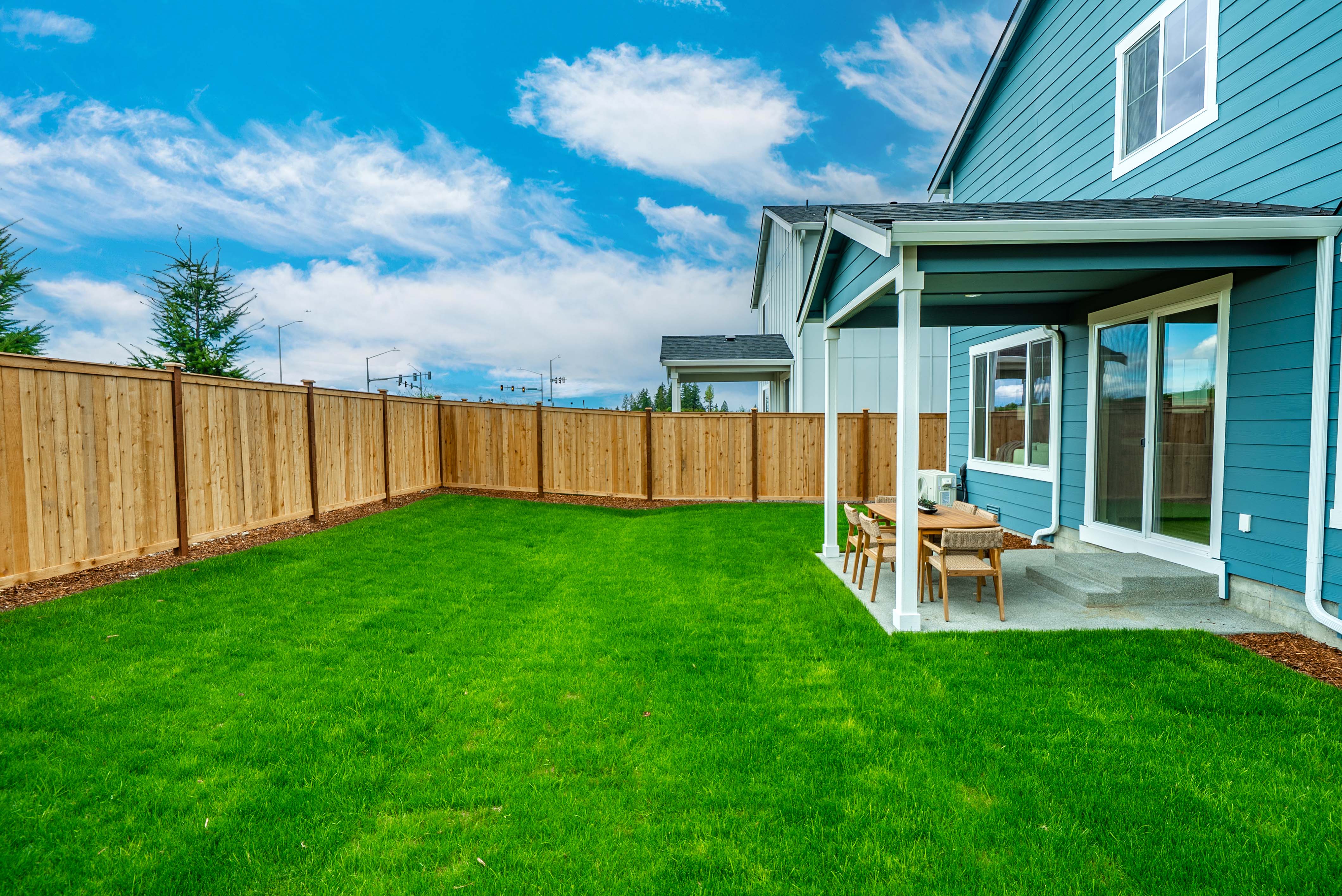 A backyard with a fence and a table and chairs.