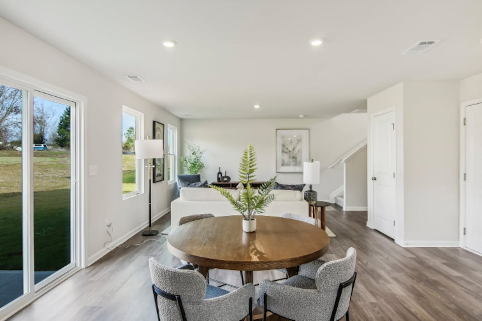 A dining room with a large glass door and a large table with chairs.