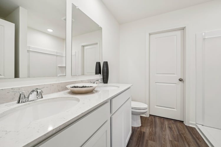 A bathroom with a sink toilet and mirror.