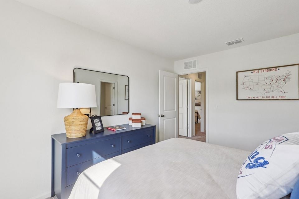 A bedroom with a bed and a mirror.