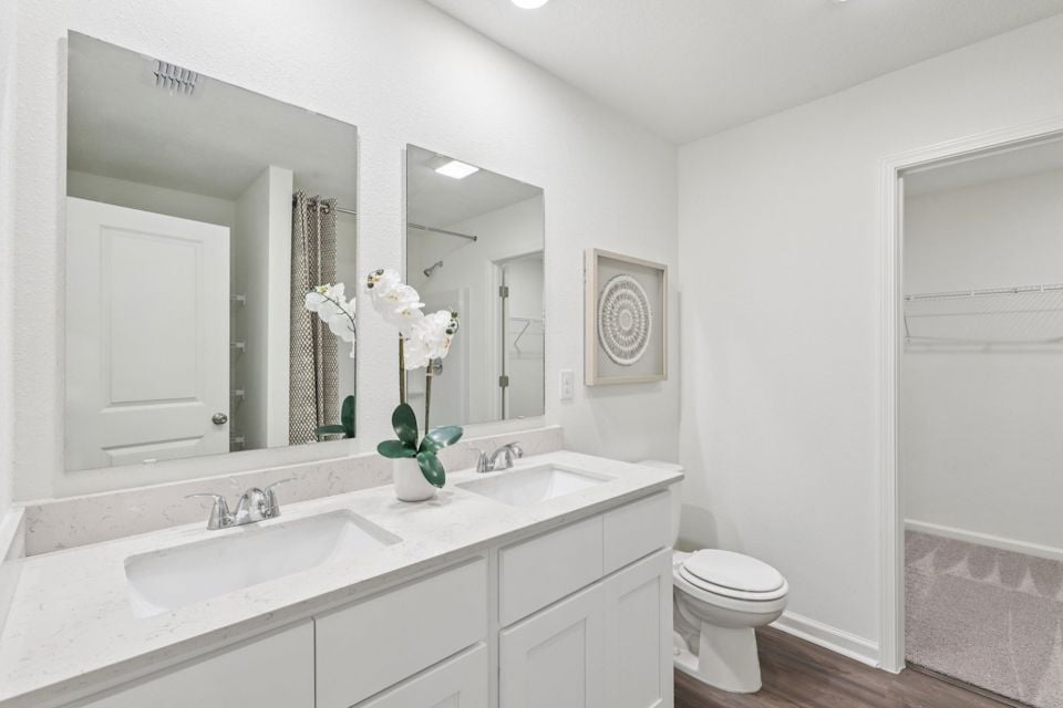 A bathroom with a sink toilet and mirror.