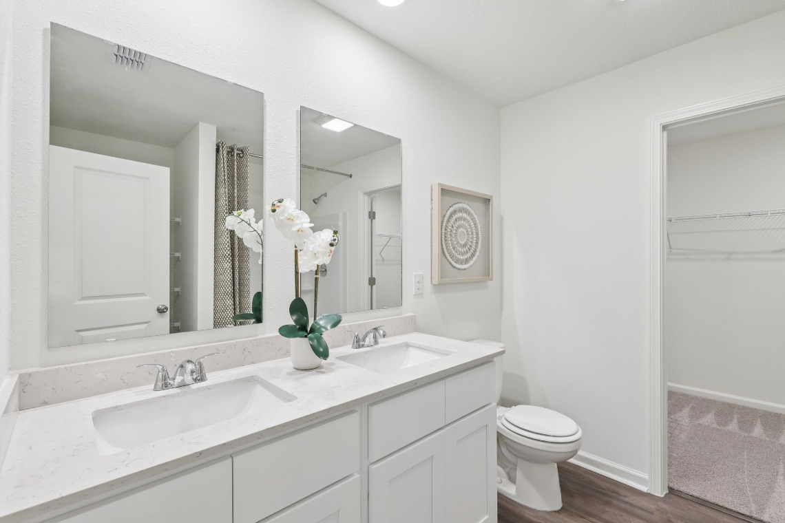 A bathroom with a sink toilet and mirror.