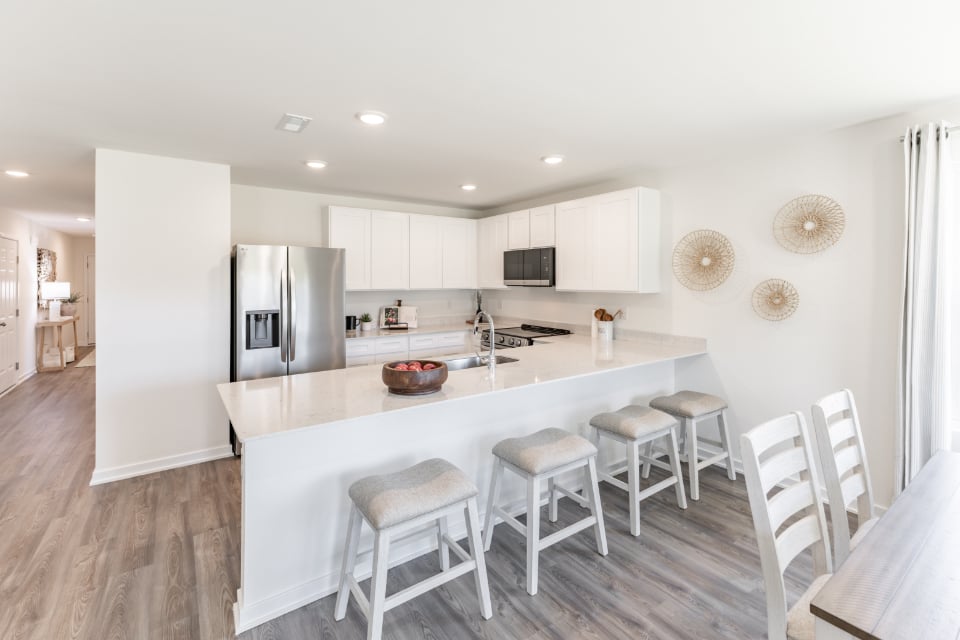 A kitchen with a bar stool and a white refrigerator.