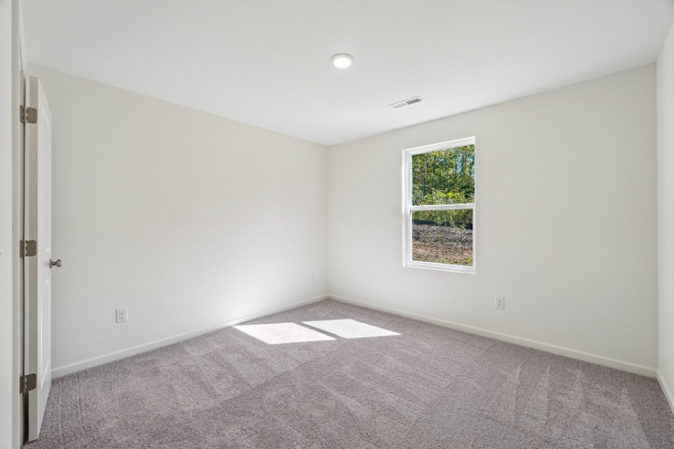 A room with a window and a rug.