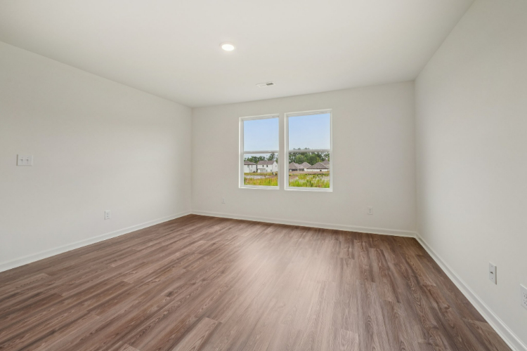 A room with a wood floor and a window with a tree outside.