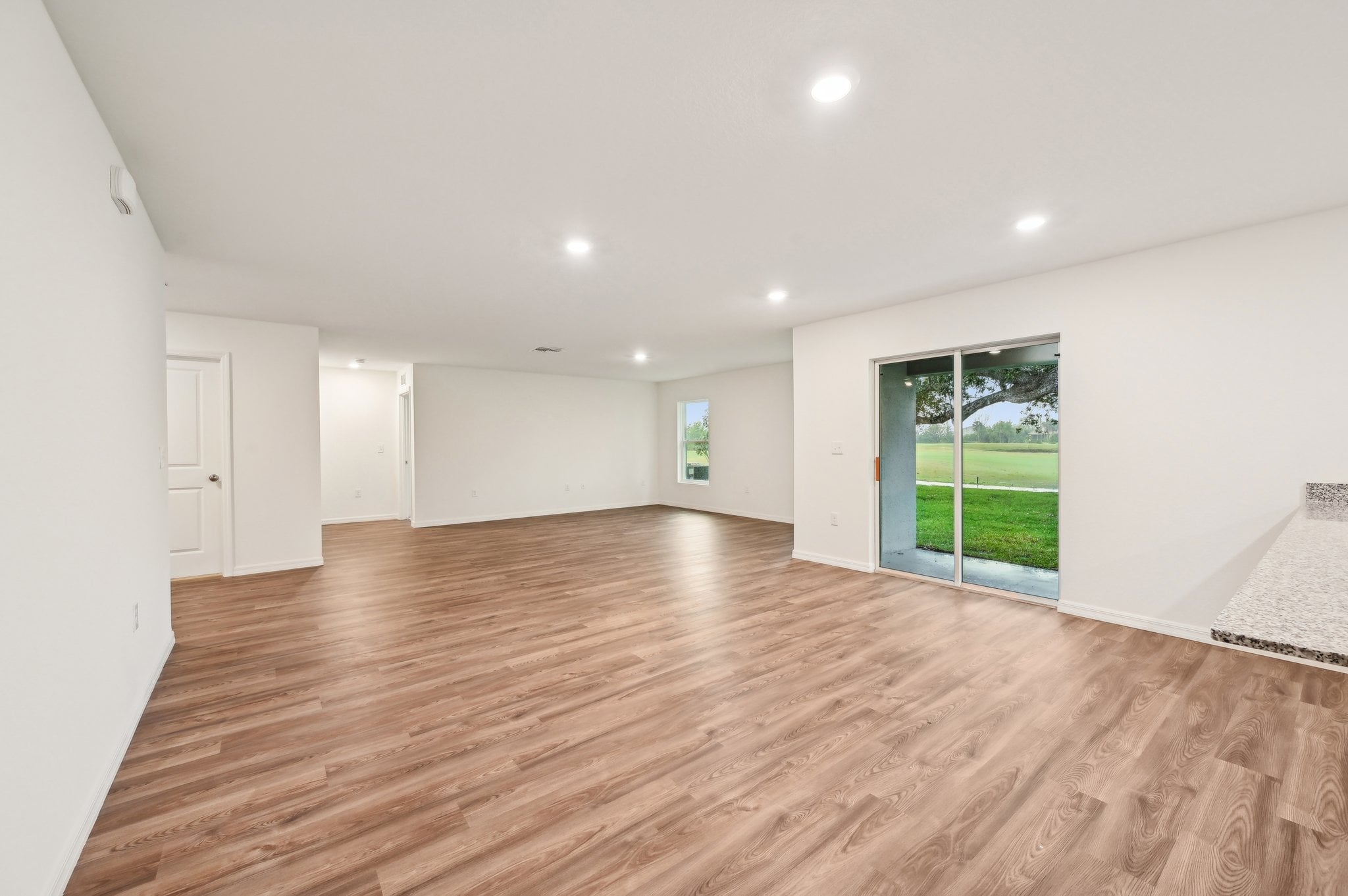 A large empty room with a wood floor and a large window.