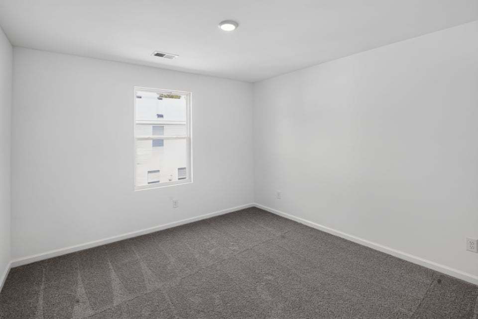 A room with a white wall and a carpet.