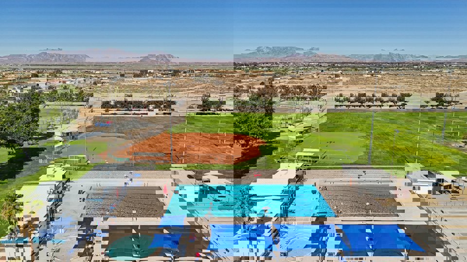 A swimming pool with a grass field and mountains in the background.