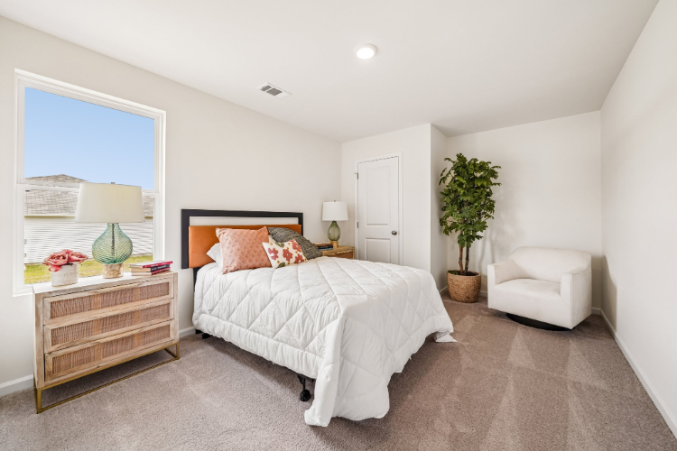 A bedroom with a bed and a chair.