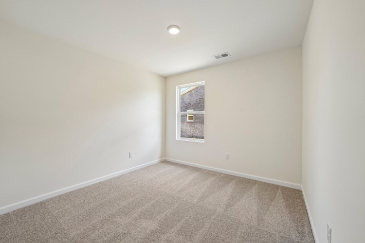 A room with a carpet and a light on the wall.