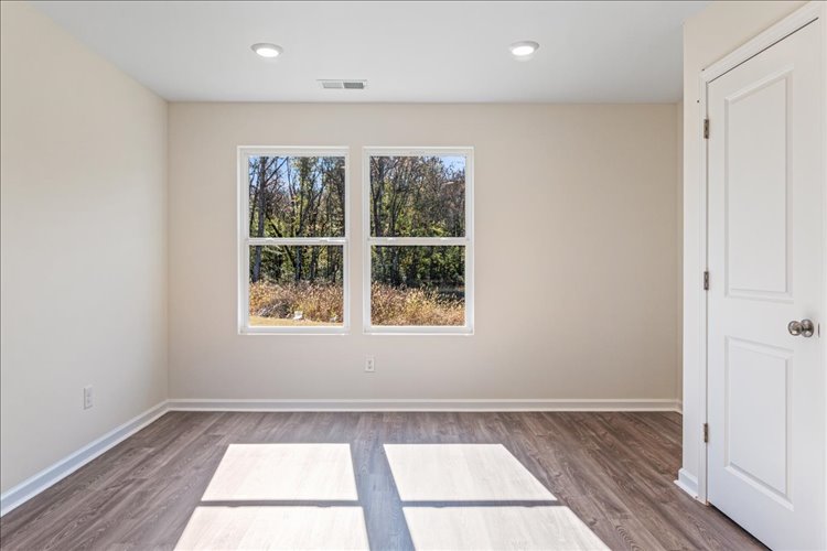 A room with a wood floor and a window with a tree outside.