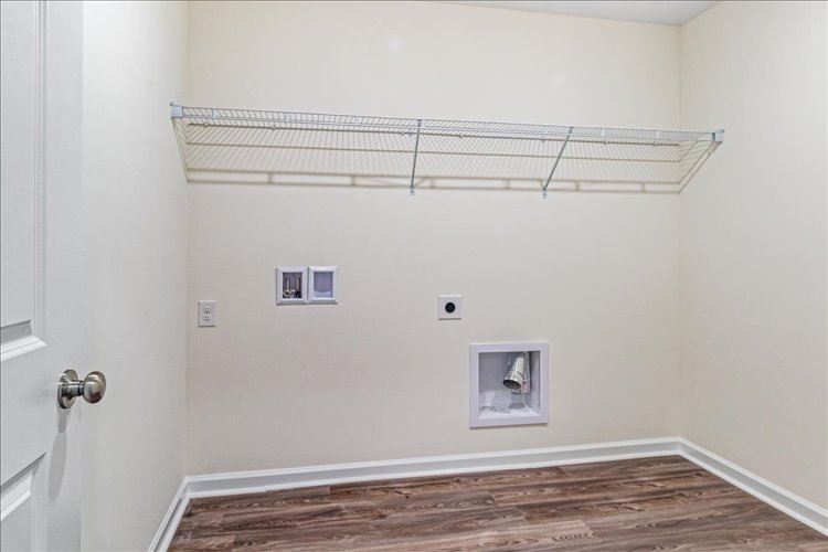 A room with a wood floor and a metal bar with a light on the wall.
