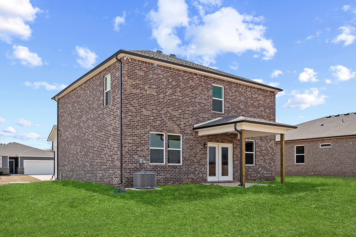 A brick house with a green lawn.