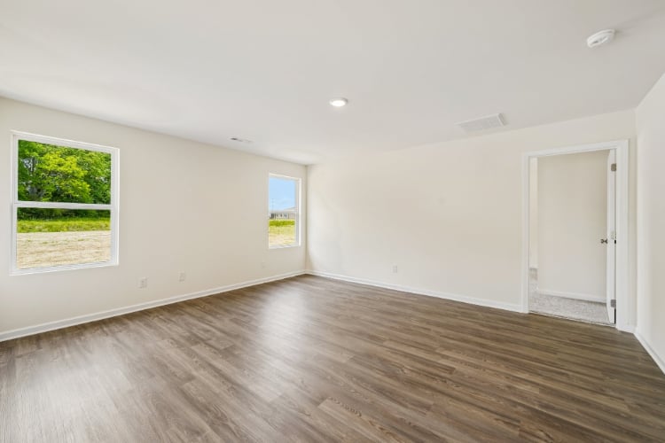 A room with a wood floor and a wood floor with a door and a window with a tree.