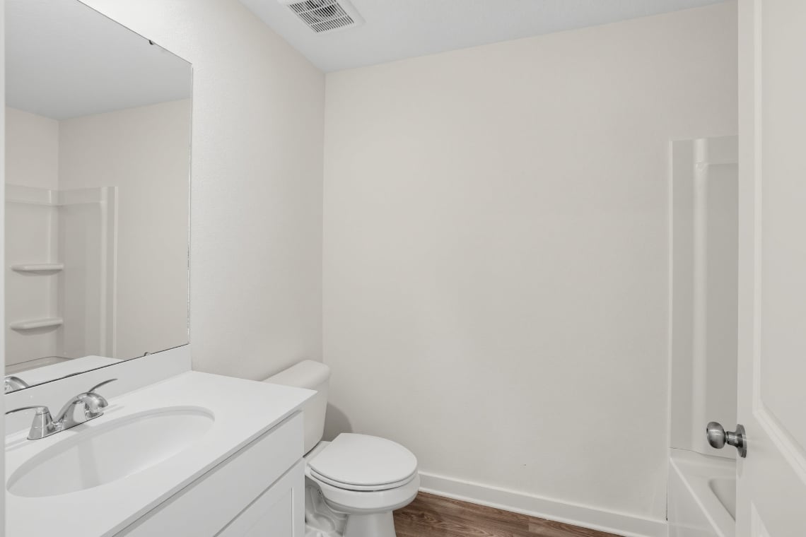 A bathroom with a toilet sink and mirror.
