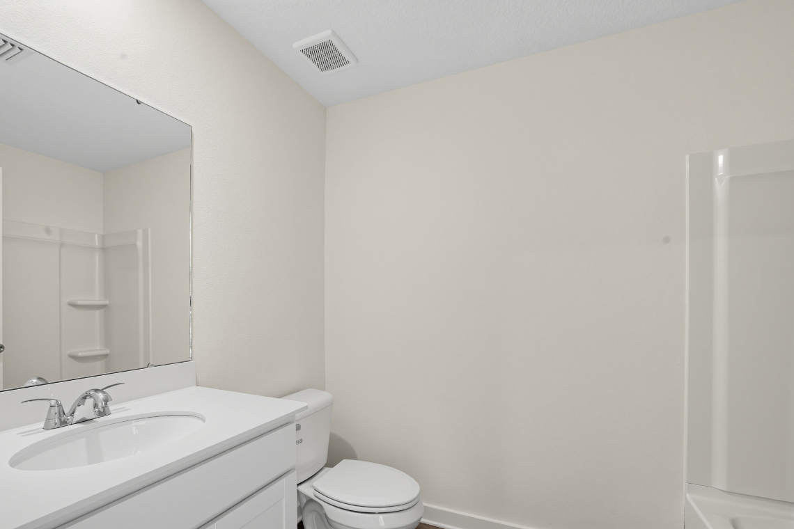 A bathroom with a sink toilet and mirror.