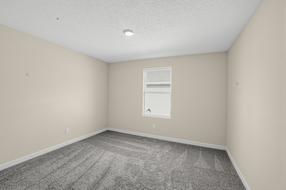 A room with a carpet and a window.