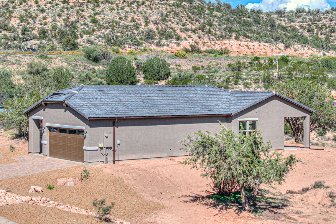 A house with a garage and a hill in the background.
