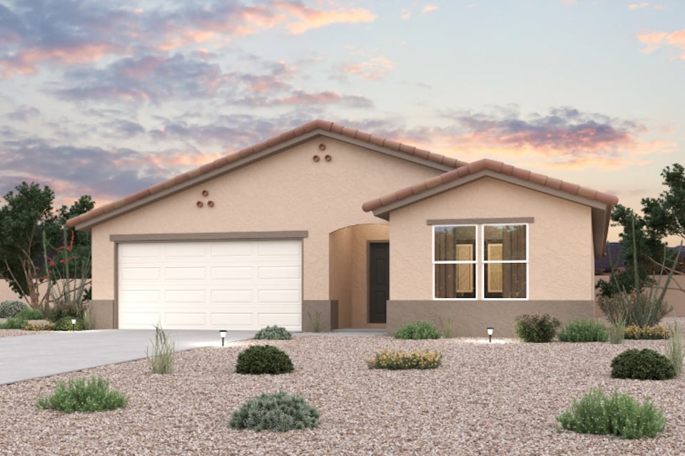 A house with a garage and bushes in front of it.