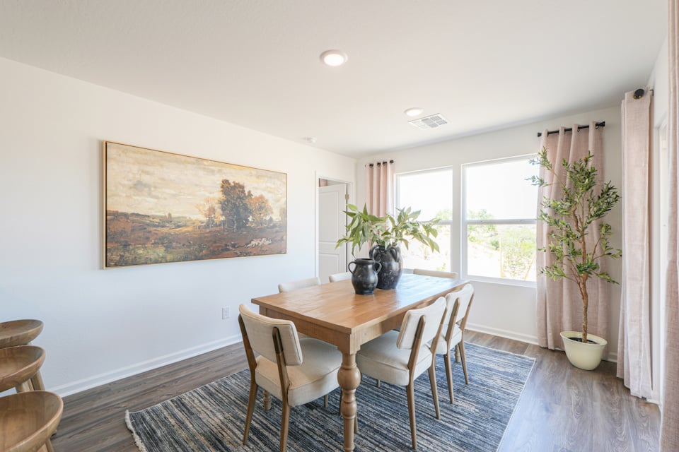 A dining room table with chairs and a painting on the wall.