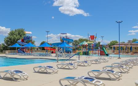 A pool with lounge chairs and a slide.