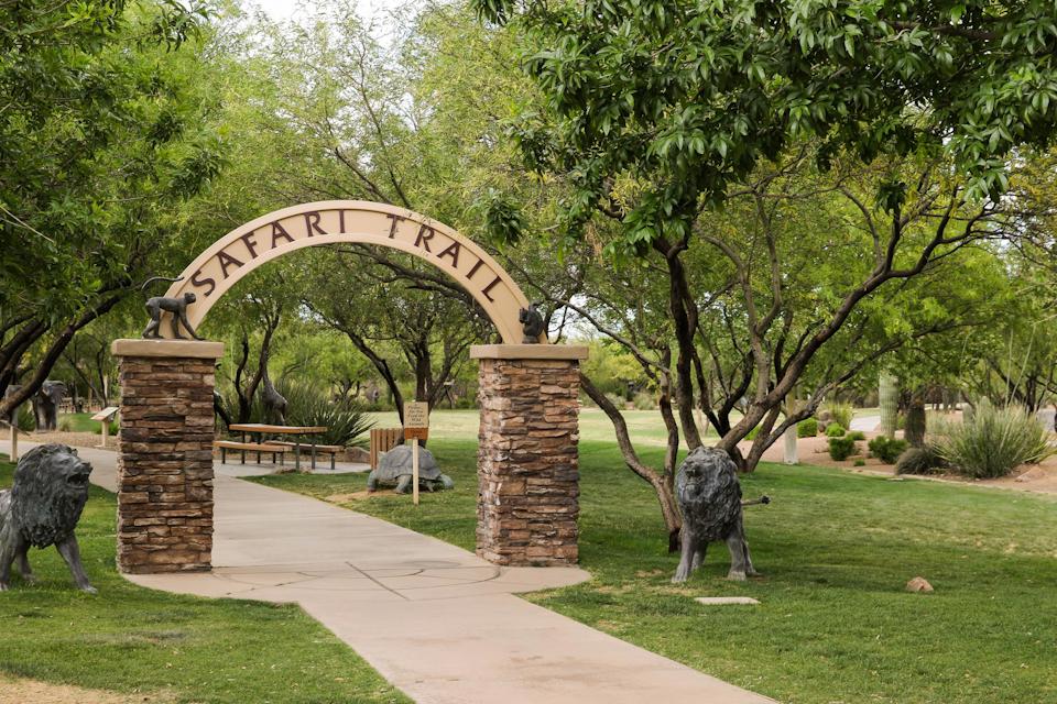 A stone archway with statues in a park.