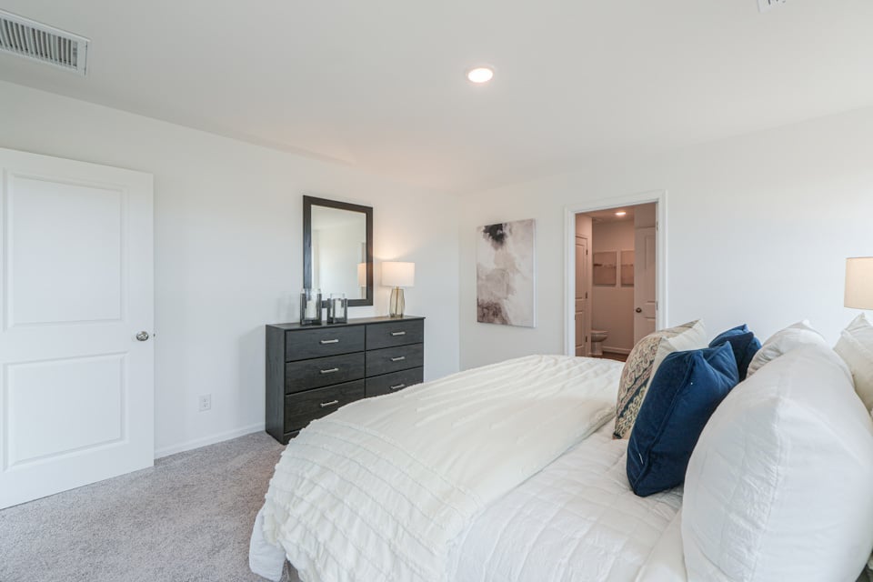 A bedroom with a bed and dresser.