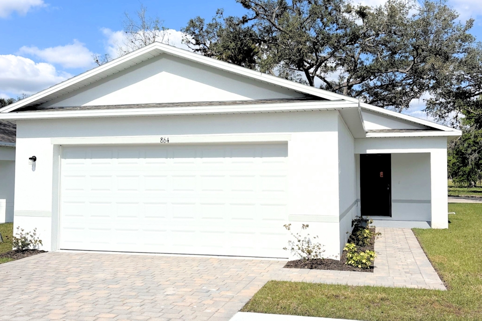 A white garage with a brick walkway.