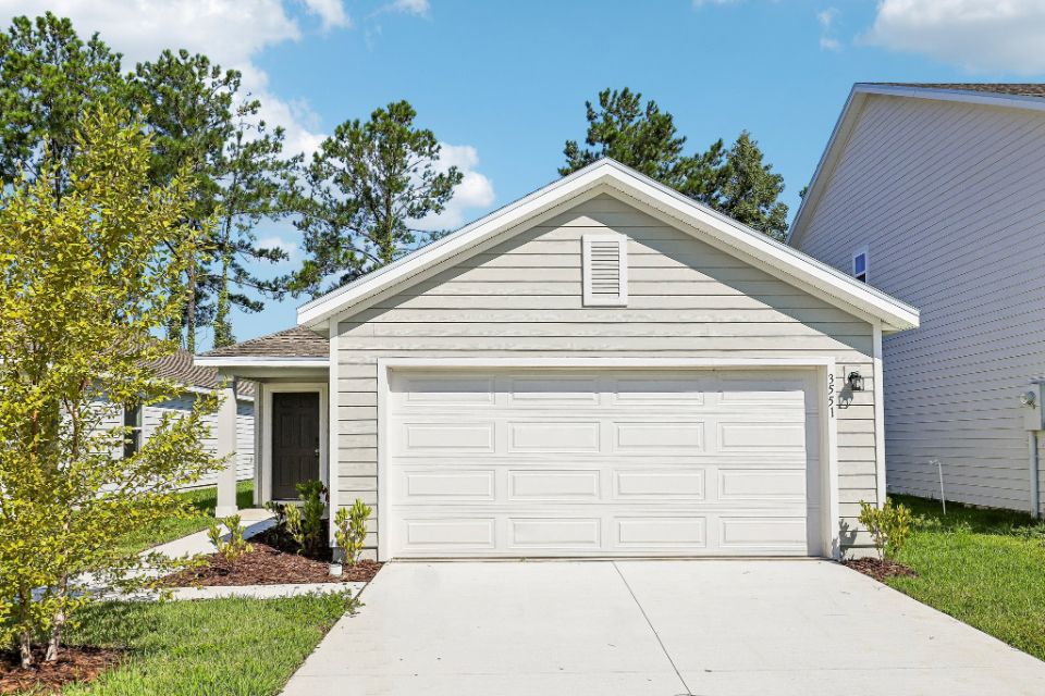 A white garage and a house with American Gothic House in the background.
