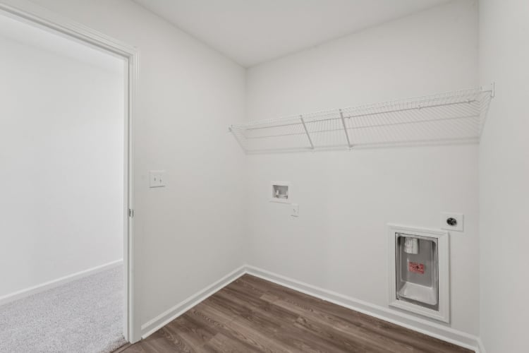 A room with a wood floor and a white wall with a vent.