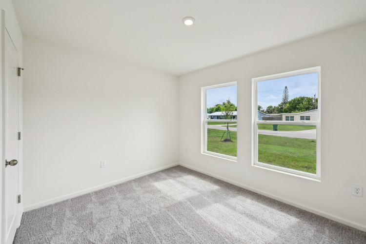 A room with a window and a door with a view of a field.