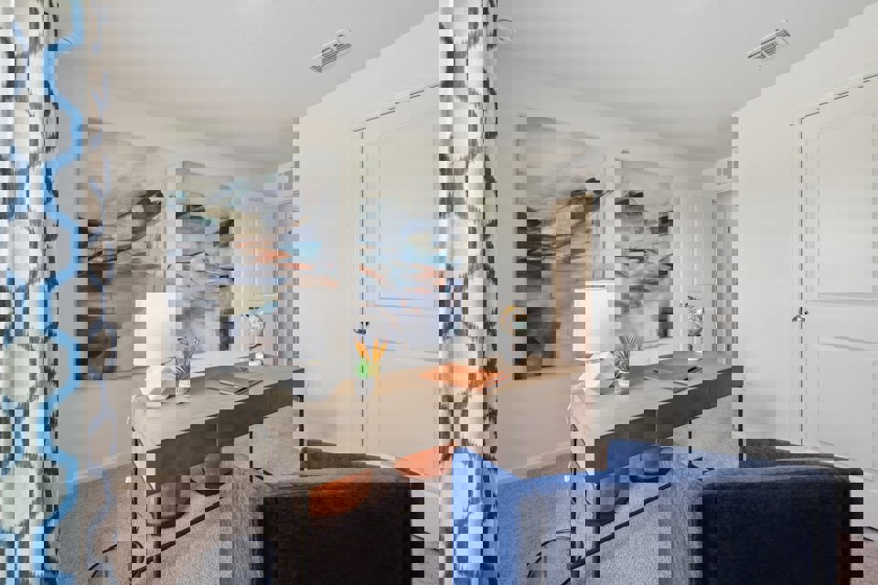 A desk with a lamp and a chair in a room with a window.