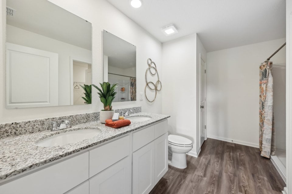 A bathroom with a sink toilet and mirror.