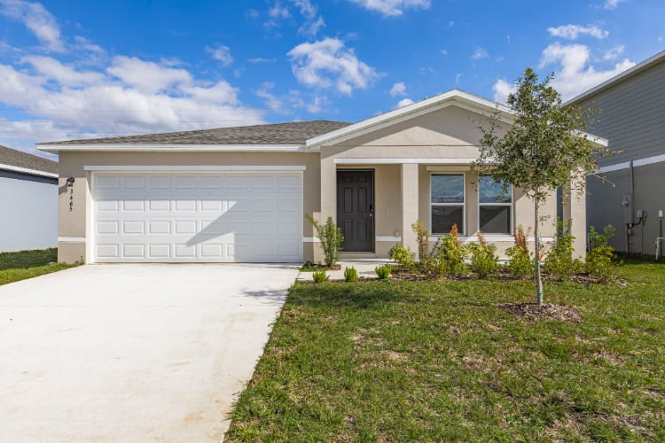 A house with a garage and a tree in the front.